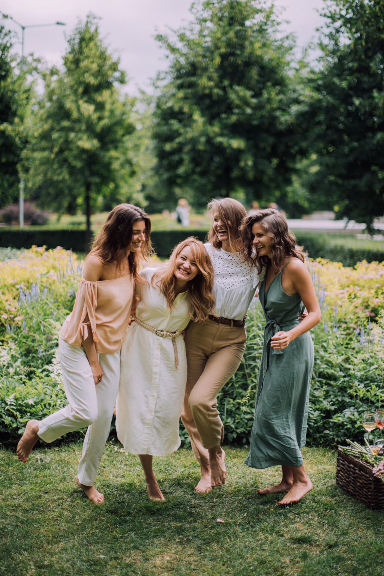 Vier Frauen lachen gemeinsam in einem sommerlichen Garten — Sinnbild für ein selbstbestimmtes, gesundes und finanziell souveränes Leben